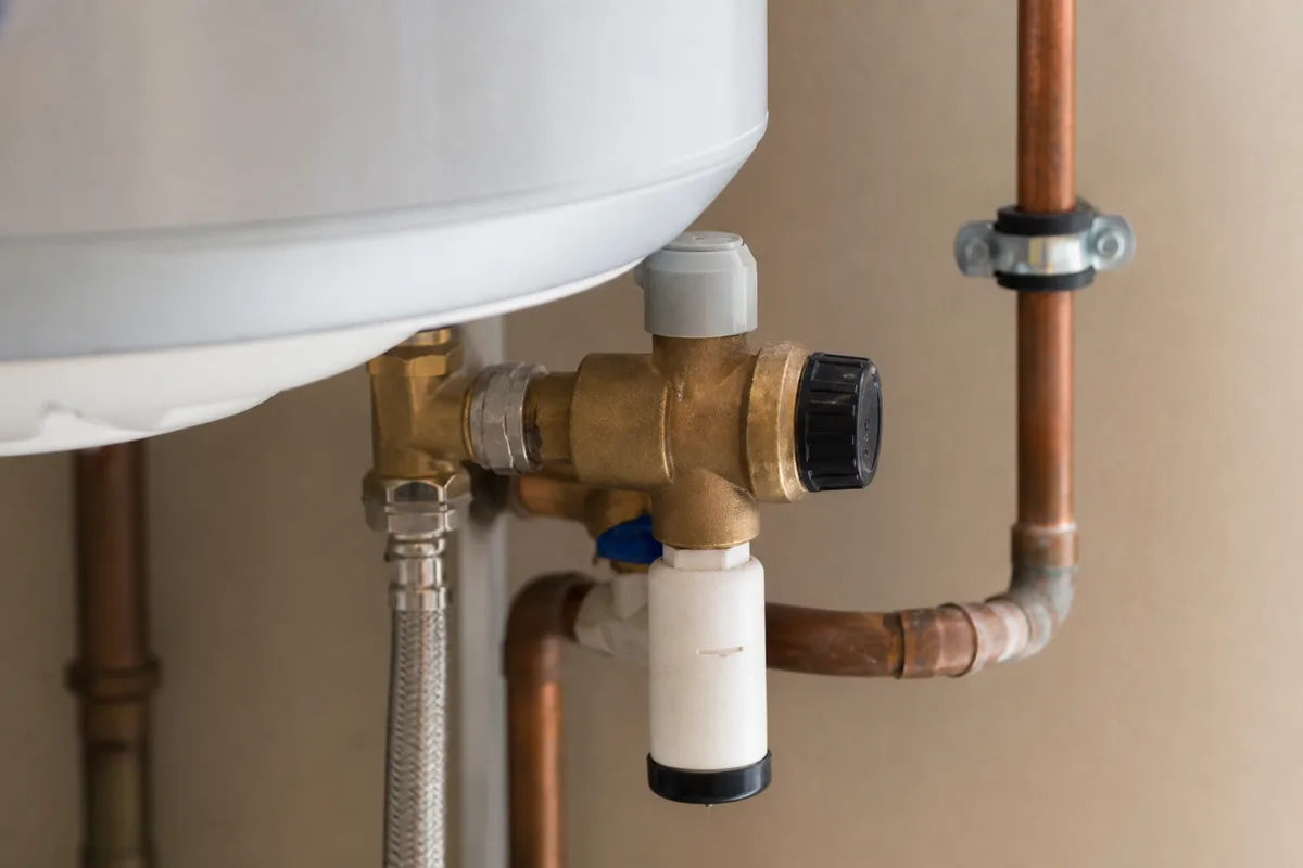 Ballon d’eau chaude et raccords en cuivre dans le cellier d’une maison landaise de plain-pied